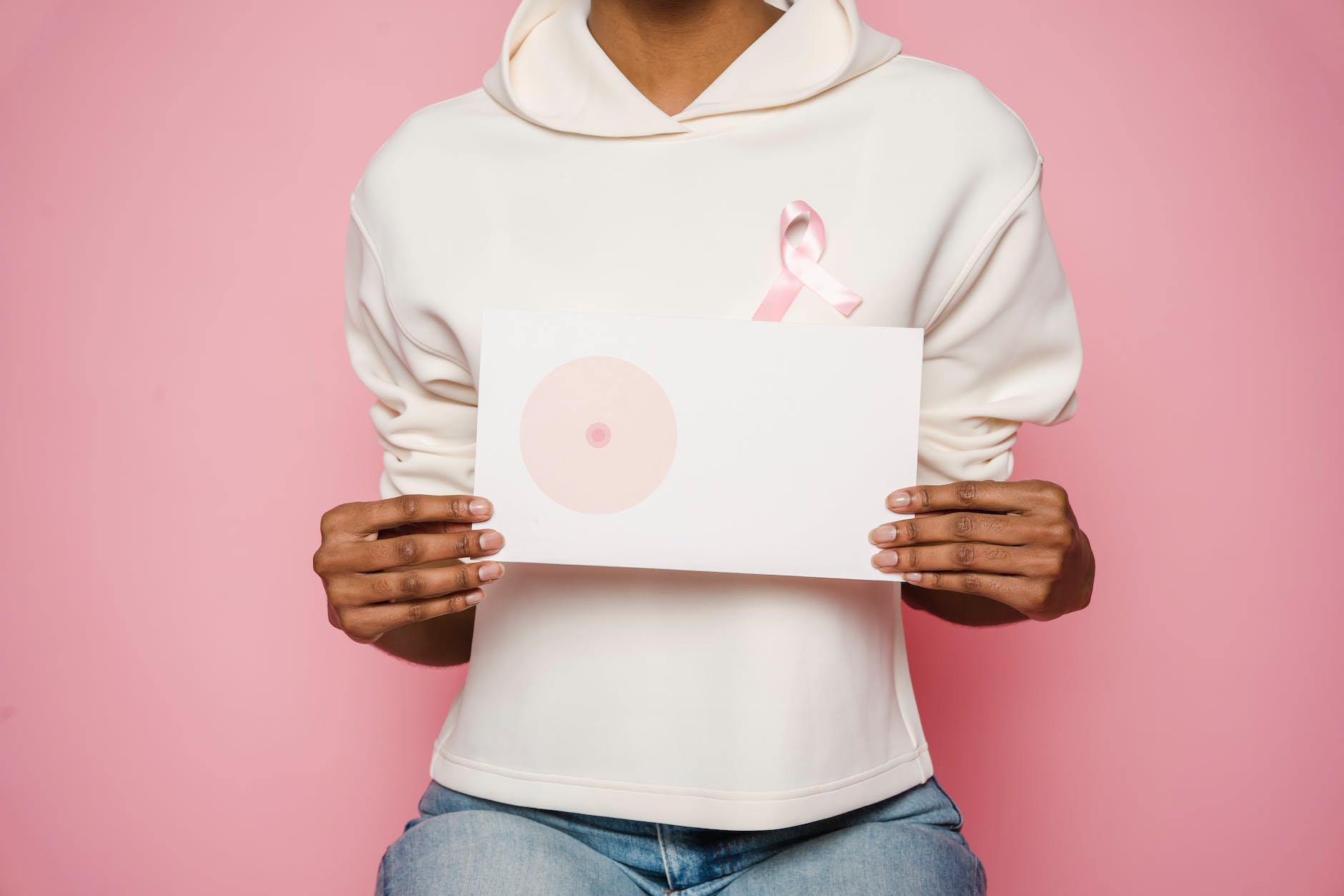 black female holding paper with painted one breast as symbol of cancer